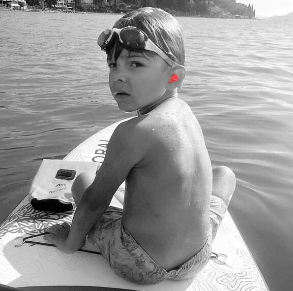 Jeune garçon sur une planche de puddle avec des protection auditives rouges